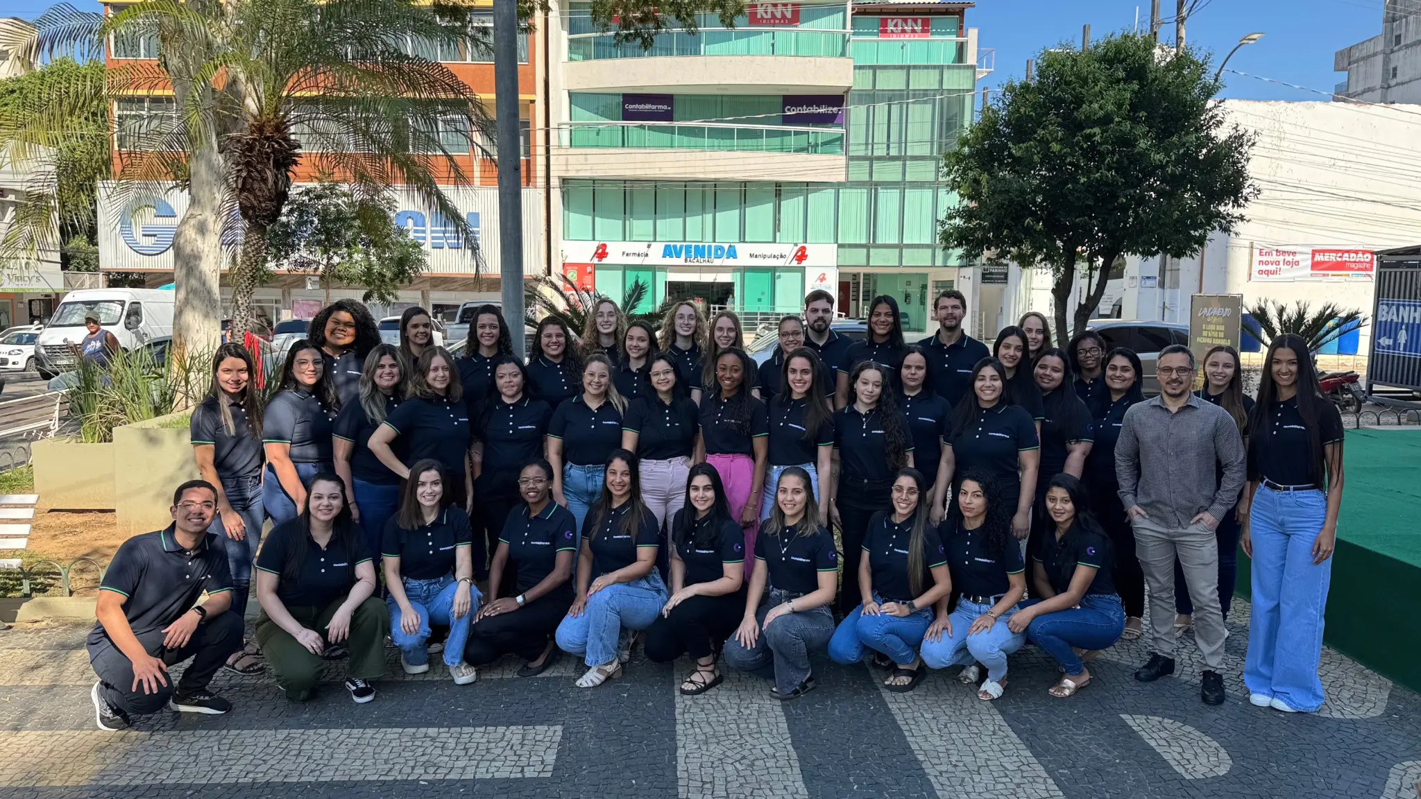 Equipe Contabilfarma reunida em frente ao escritório, todos de camisa polo azul-marinho
