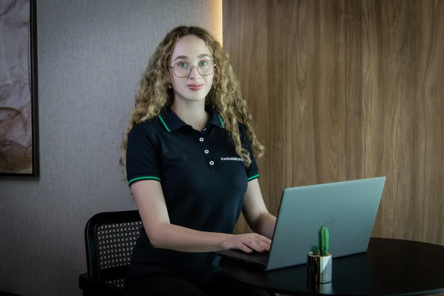 Colaboradora com notebook olhando para a câmera
